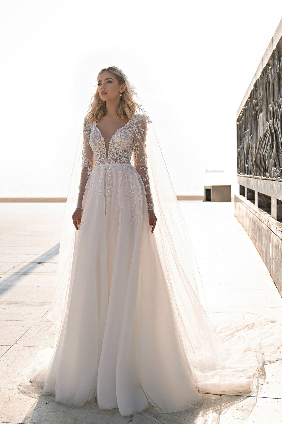 Ivory A-line wedding dress with a deep V-neck, long lace sleeves, and a flowing full skirt
