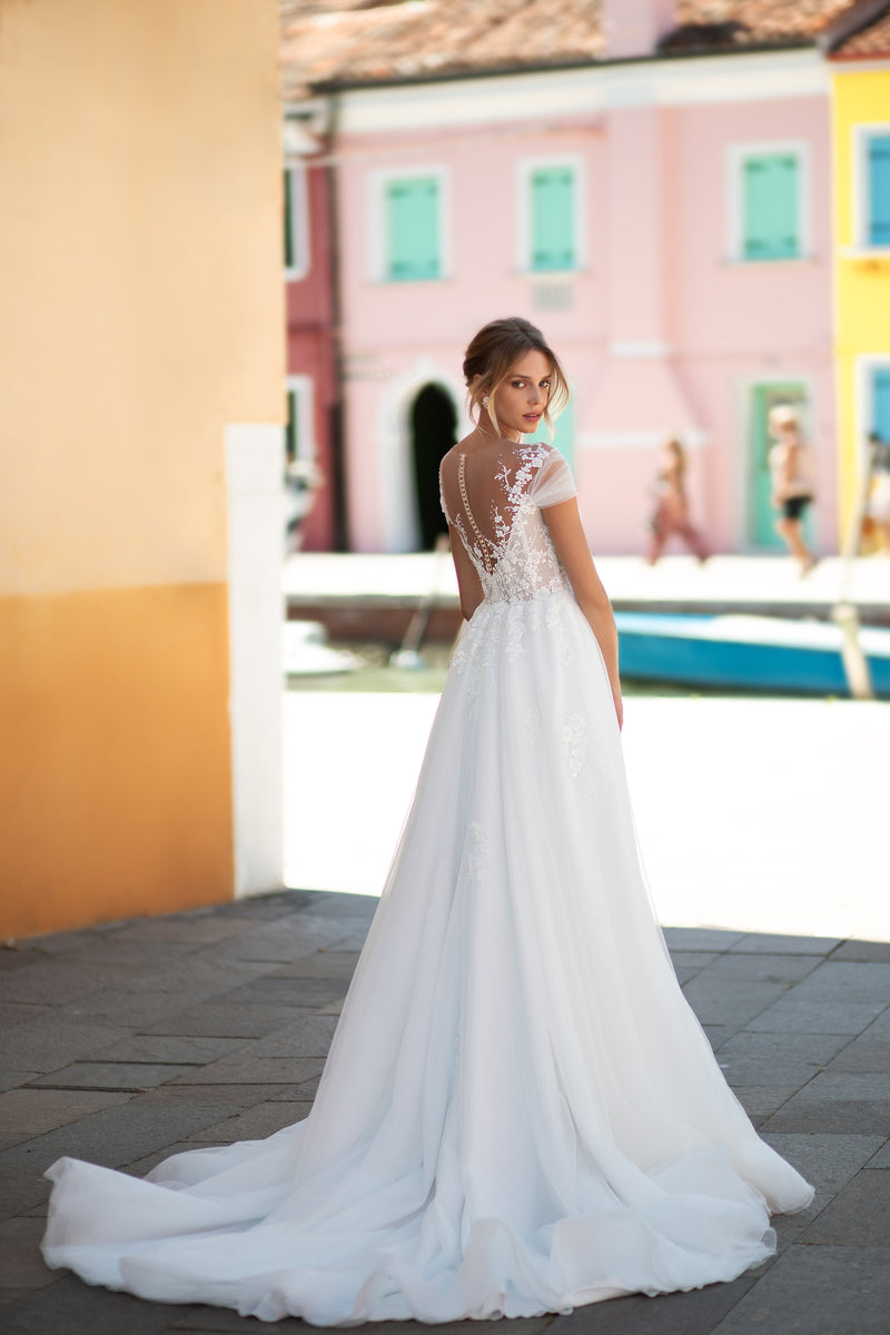 Sheer lace back with covered buttons and a sweeping train on an ivory A-line wedding dress