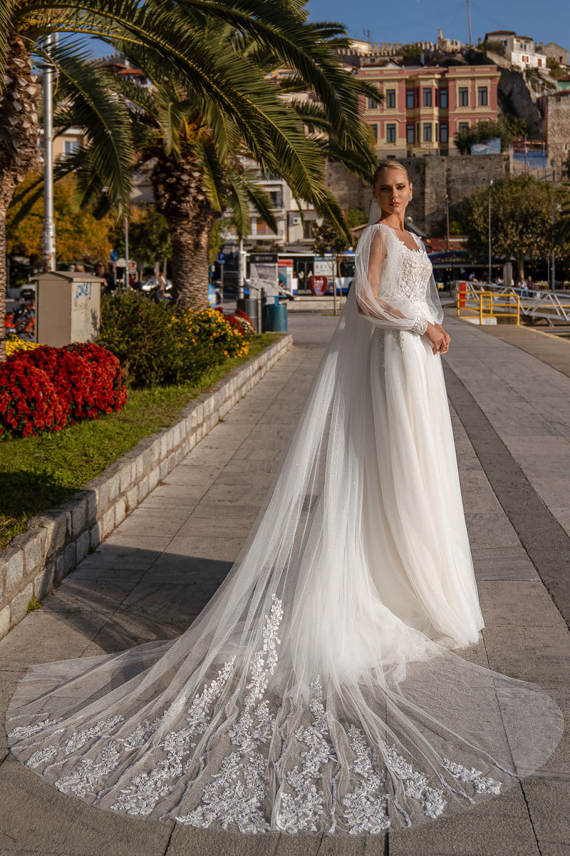 Ivory A-line wedding dress with a beaded lace bodice, sheer long sleeves, and a sweeping lace-edged train