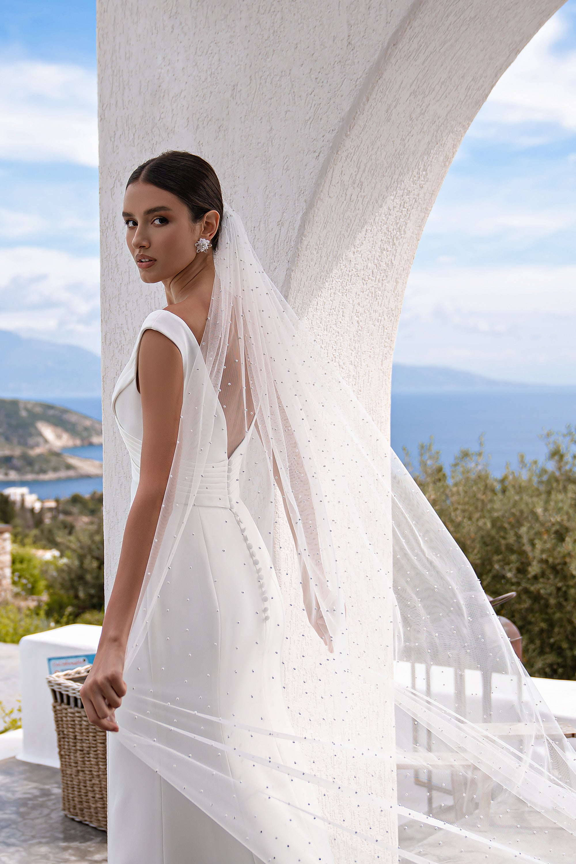 Sheer white wedding veil shown from the side, with pearl details and a long, wide drape