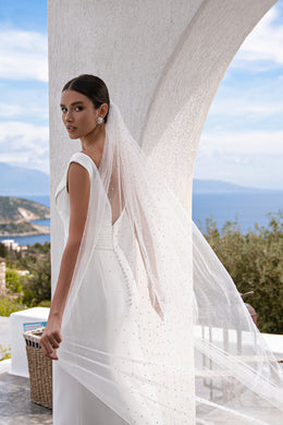 Sheer white wedding veil shown from the side, with pearl details and a long, wide drape