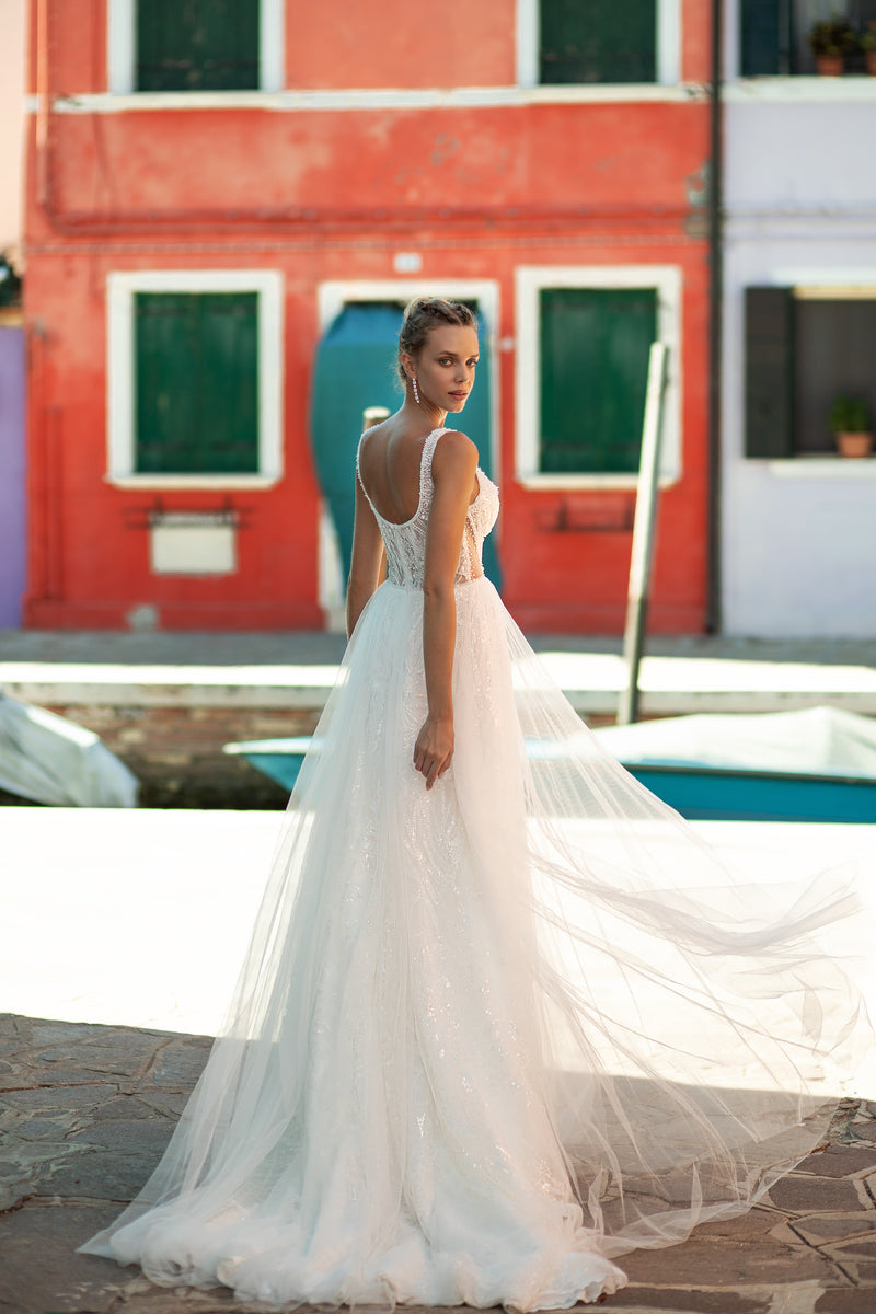 Sheer lace-back wedding dress with beaded straps, an A-line skirt, and a flowing train