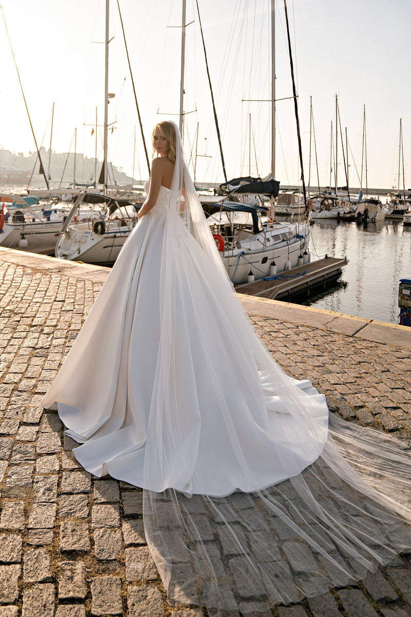 Ivory wedding dress shown from the back, with a voluminous ball gown skirt and trailing train