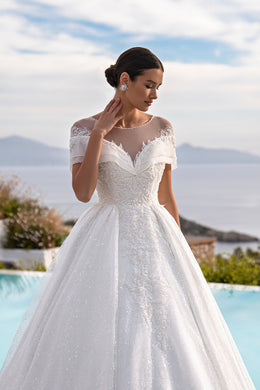 White ball gown wedding dress with a sweetheart neckline, sheer illusion panel, lace sleeves, and beaded bodice