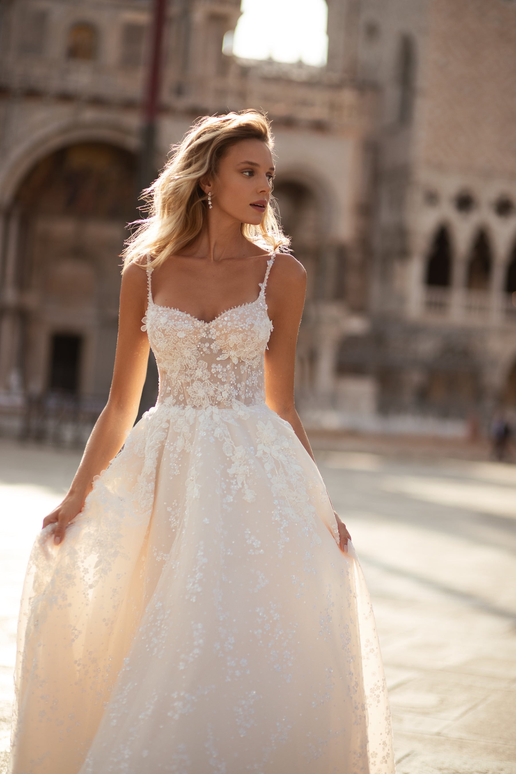 Ivory wedding dress with a sweetheart neckline, slender straps, floral lace bodice, and flowing A-line skirt