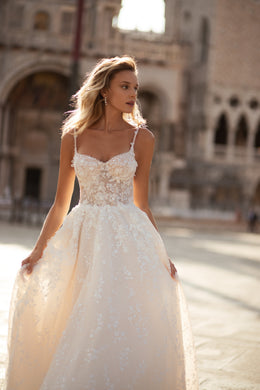 Ivory wedding dress with a sweetheart neckline, slender straps, floral lace bodice, and flowing A-line skirt