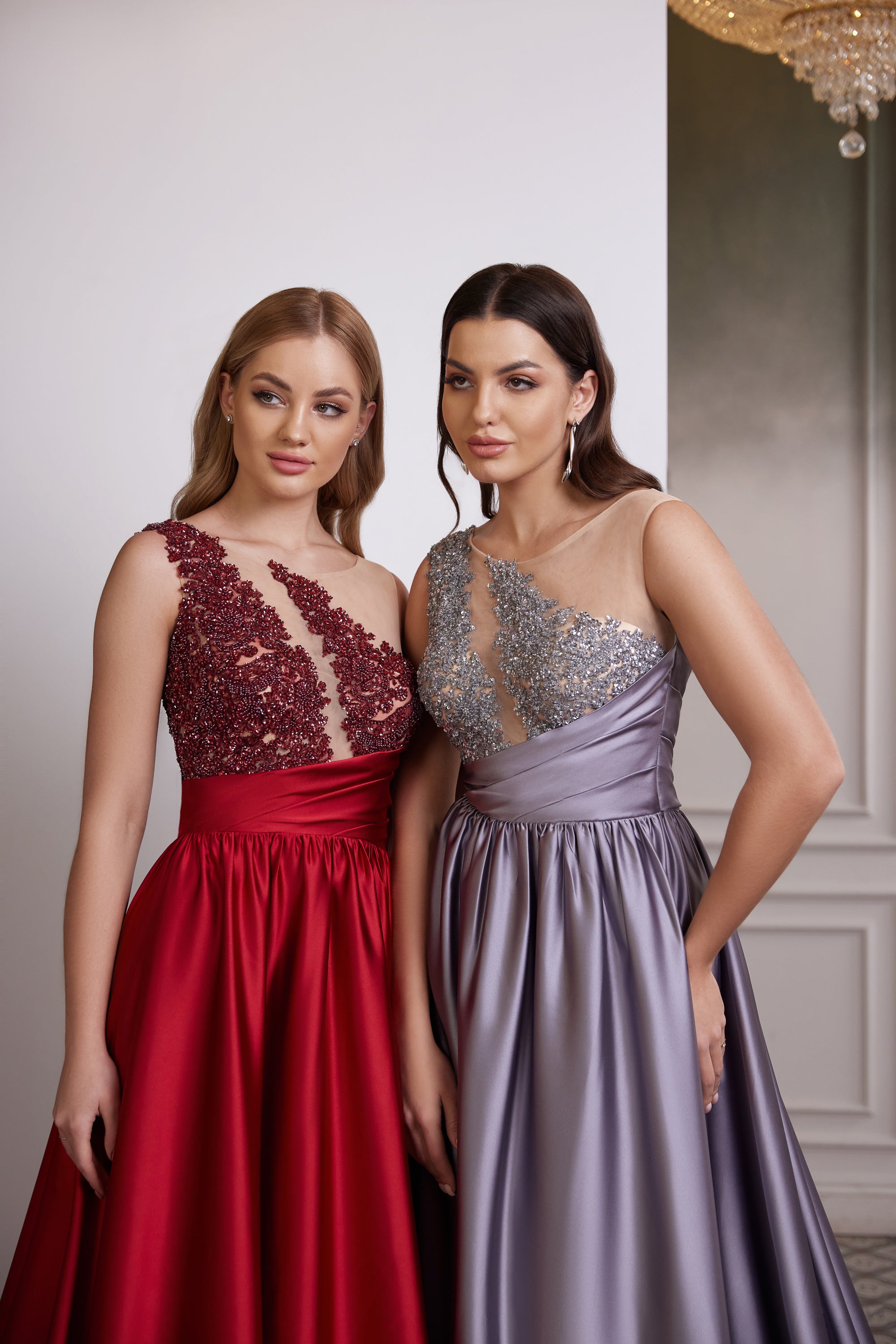 Close-up of red and lavender evening dress bodices with asymmetric necklines, sheer mesh, and sparkling beadwork