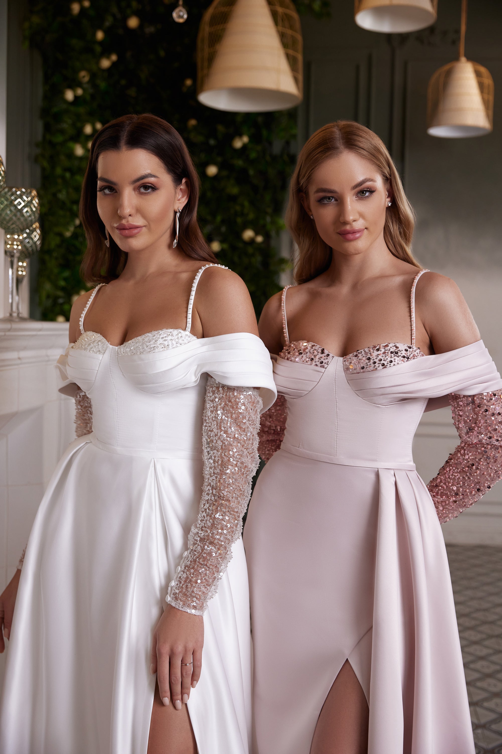 Close-up of white and blush evening dresses featuring beaded bodices, off-shoulder bands, straps, and slits