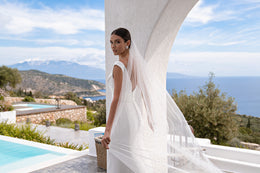 Side view of an ivory wedding dress showing its fitted sheath silhouette and low back