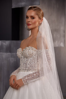Sheer white sparkling wedding veil draped from a bridal updo and falling over the shoulder