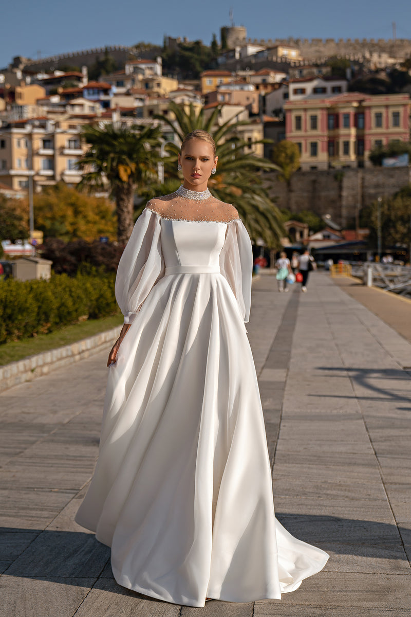 White A-line wedding dress with a beaded illusion neckline, sheer long sleeves, and a flowing train