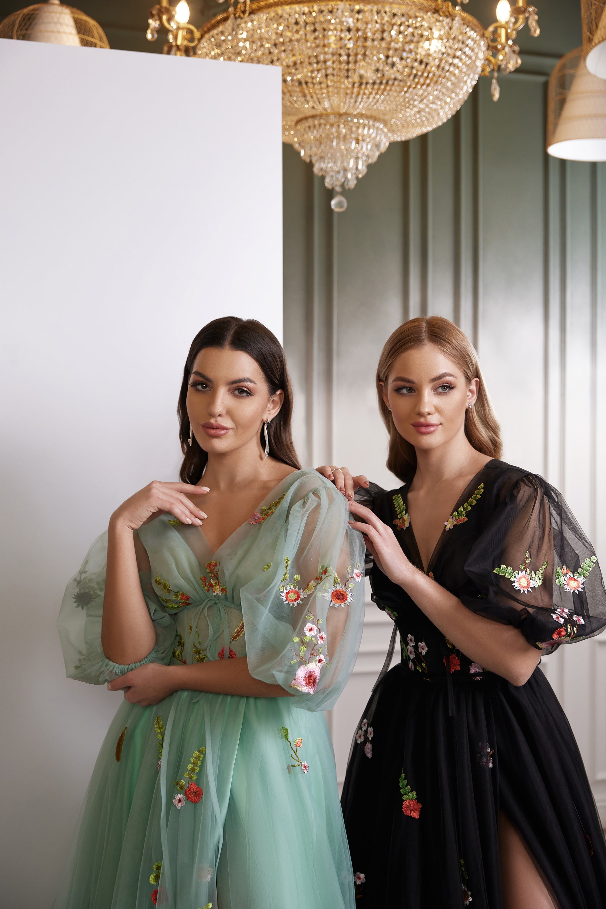 Close-up of black evening dress with a V-neckline, sheer puff sleeves, and colorful floral embroidery