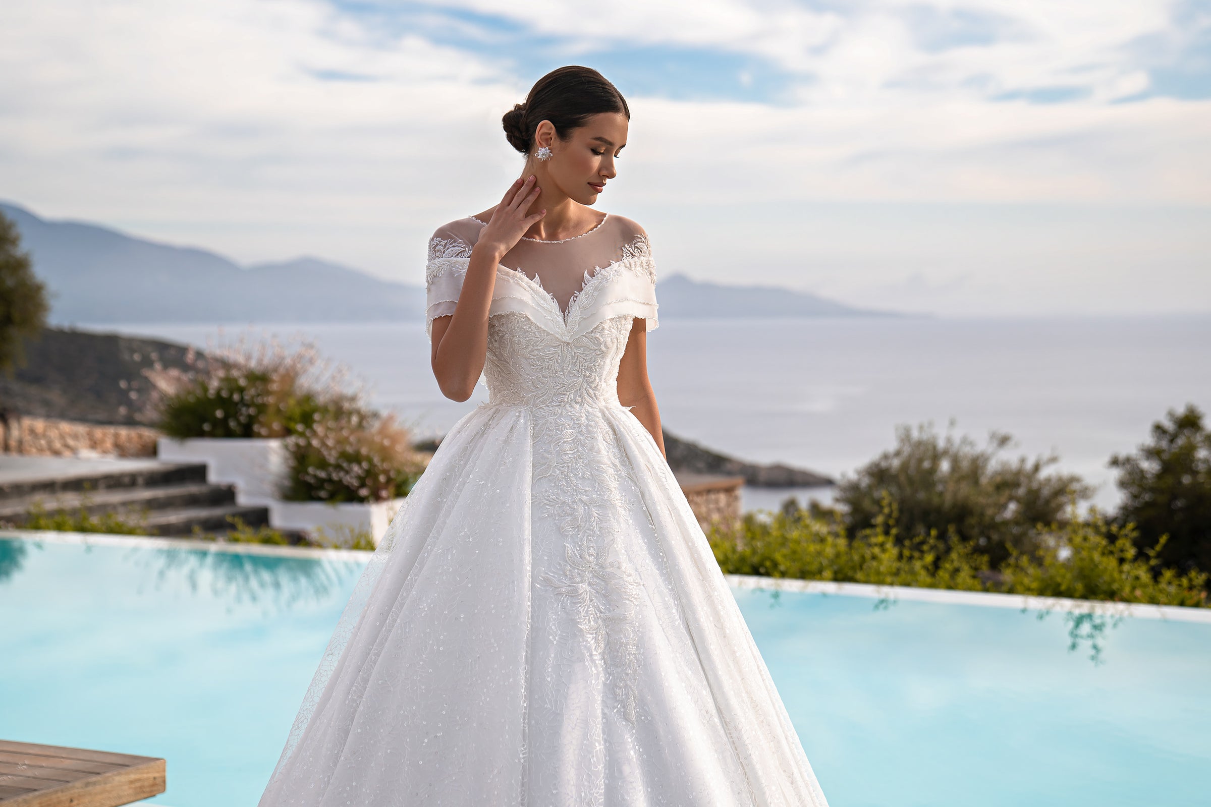 White wedding dress with an illusion neckline, short lace sleeves, fitted bodice, and flowing ball gown skirt