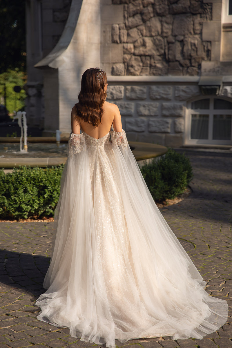 Open low back and sweeping sheer train on an ivory wedding dress with glittering fabric