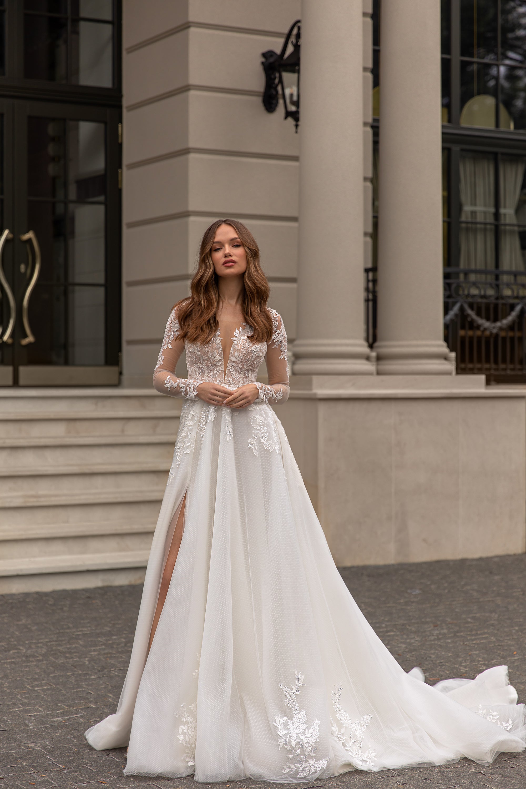 Ivory A-line wedding dress with plunging V-neck, sheer lace sleeves, floral appliqués, and a long train
