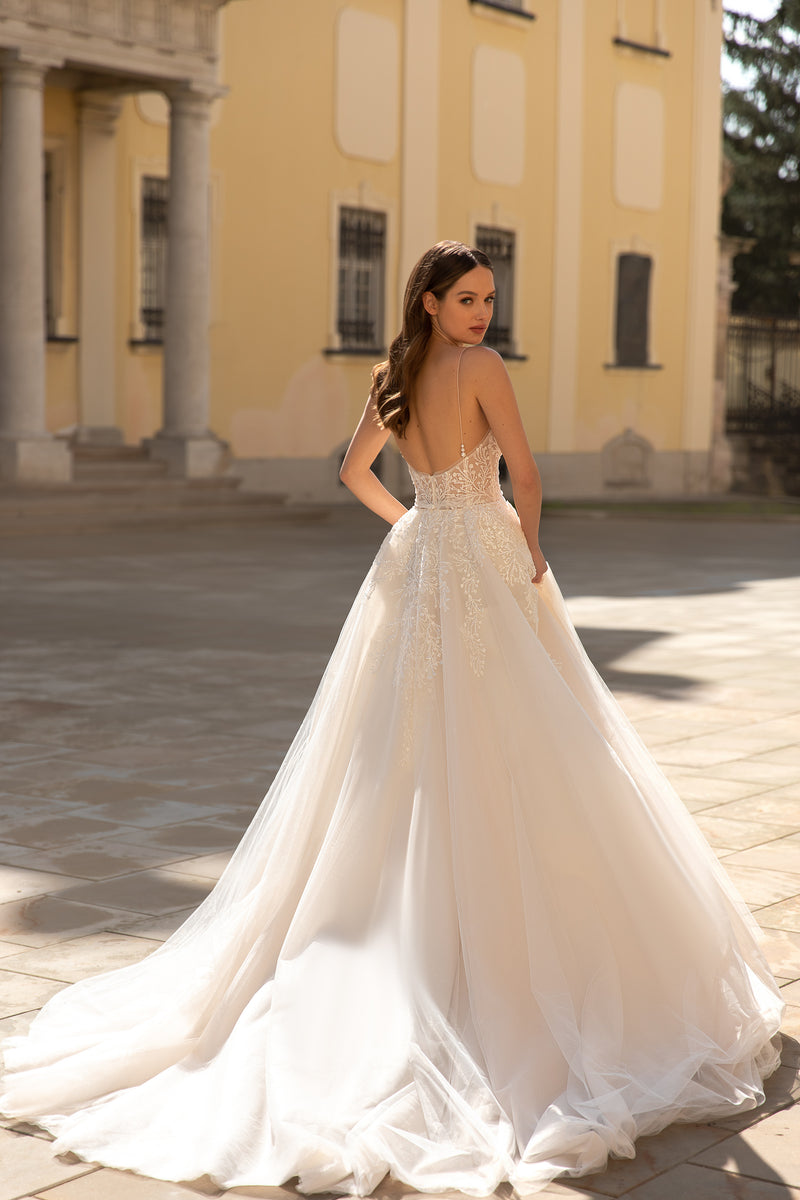 Open-back ivory wedding dress with thin straps, lace detailing, and a sweeping train