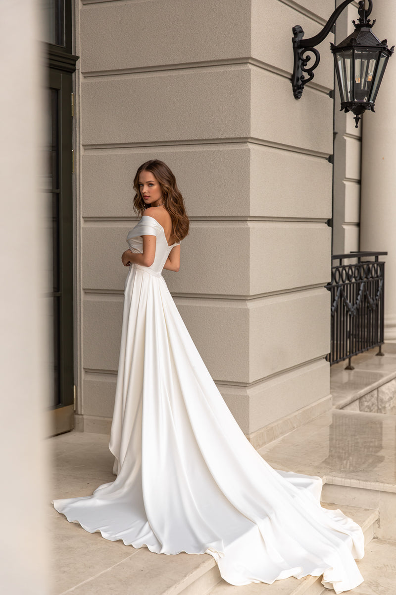 White wedding dress with short sleeves and a flowing detachable overskirt extending into a long train