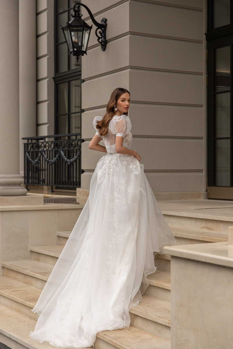 Ivory wedding dress with short sheer puff sleeves, floral lace, and a long flowing train