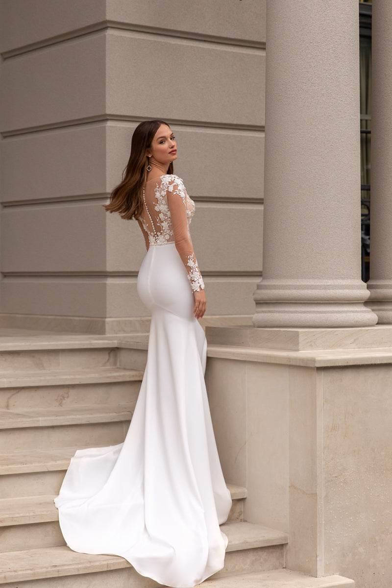 Sheer lace back and long train on an ivory fitted wedding dress with illusion sleeves