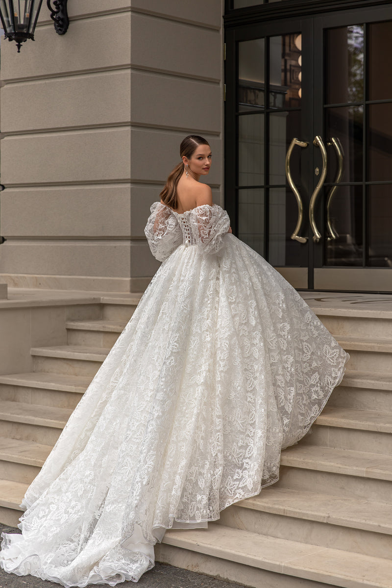 Ivory wedding dress showing an open back, lace sleeves, full ball-gown skirt, and long lace train