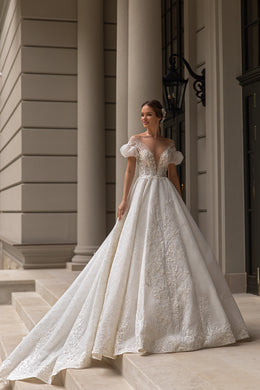 Ivory ball gown wedding dress with a deep V-neckline, puff sleeves, sparkling lace appliqués, and a long train