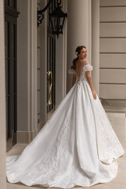 Open-back ivory wedding dress with short puff sleeves, shimmering lace appliqués, and a sweeping train