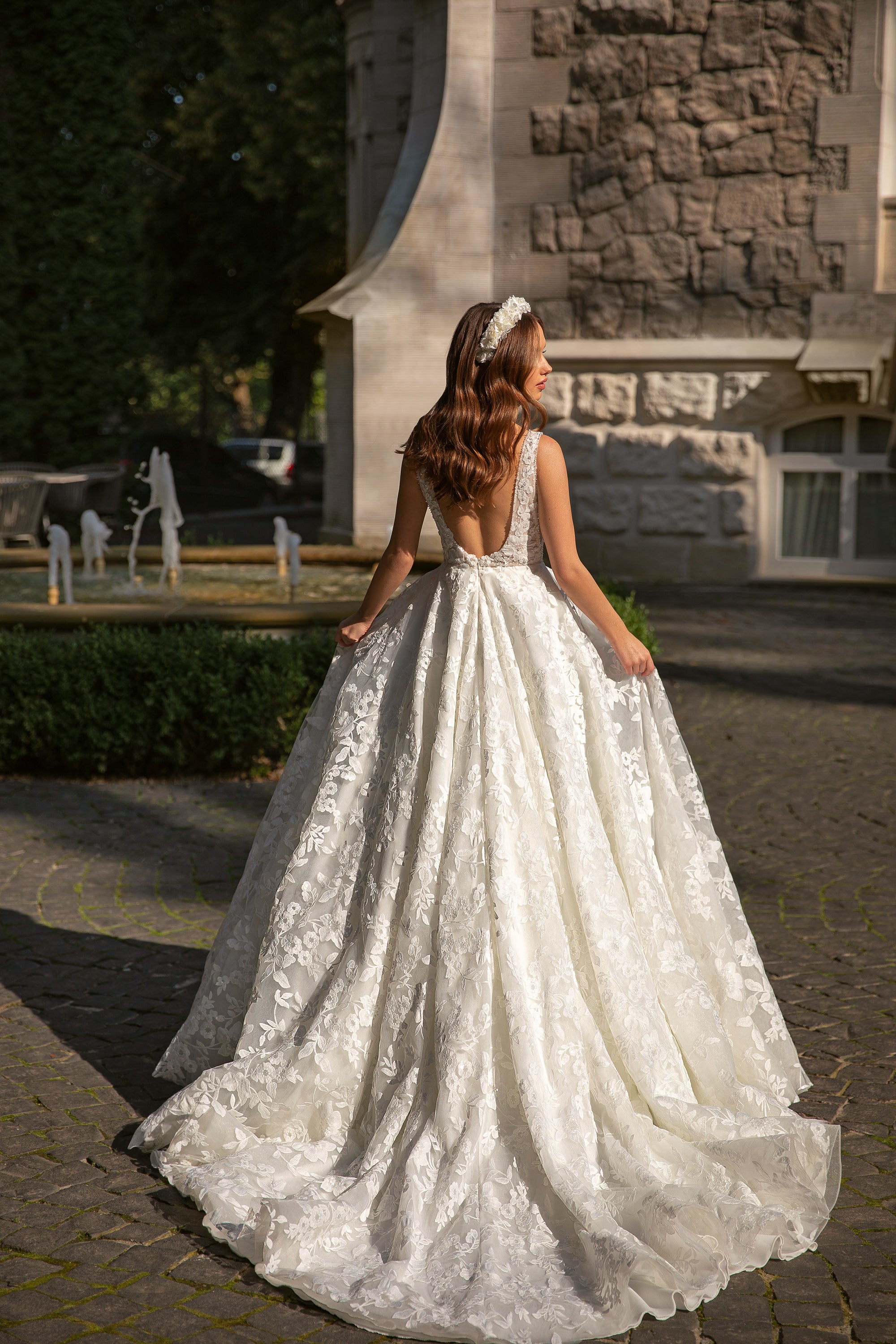 Back view of an ivory wedding dress with a low open back, floral lace, and sweeping ball gown skirt