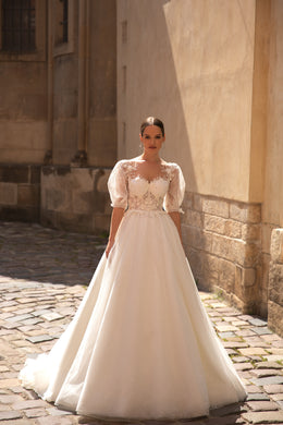 Ivory A-line wedding dress with a sparkling skirt, sheer puff sleeves, lace bodice, and court train