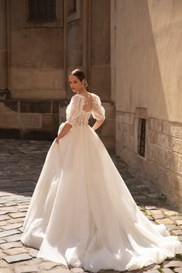 Ivory wedding dress with an open lace back, sheer short sleeves, full A-line skirt, and long train