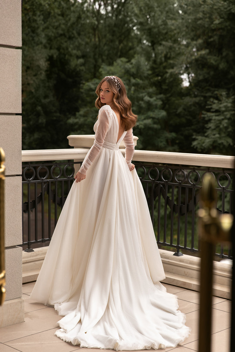 Low open back and sweeping train on an ivory long-sleeve wedding dress with glittering tulle