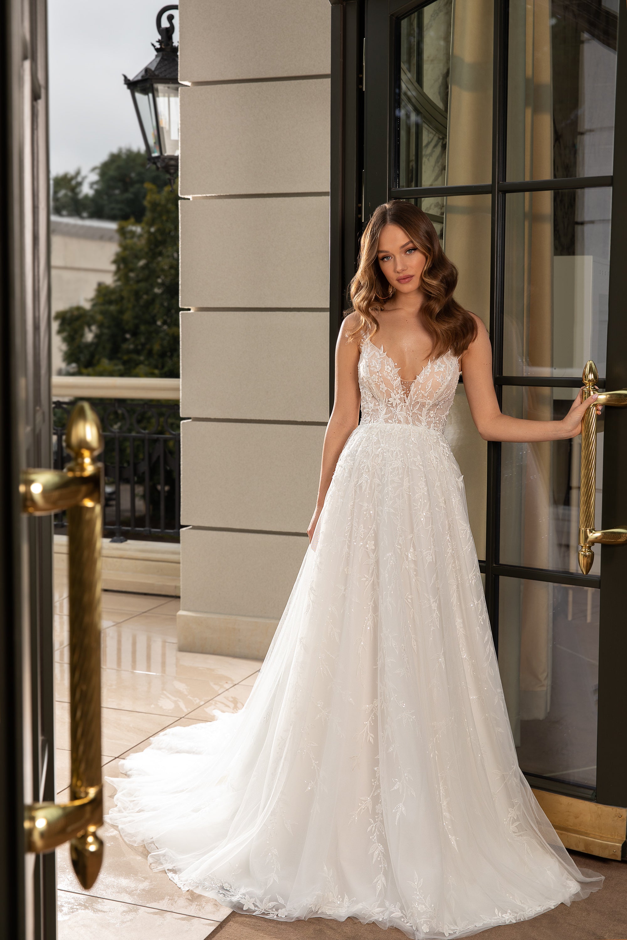 Ivory A-line wedding dress with a lace V-neck bodice, spaghetti straps, and a flowing tulle train