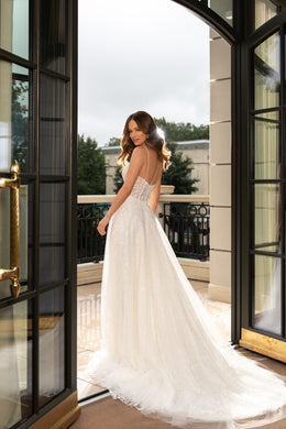 Open low back and delicate straps on an ivory A-line wedding dress with a sweeping tulle train