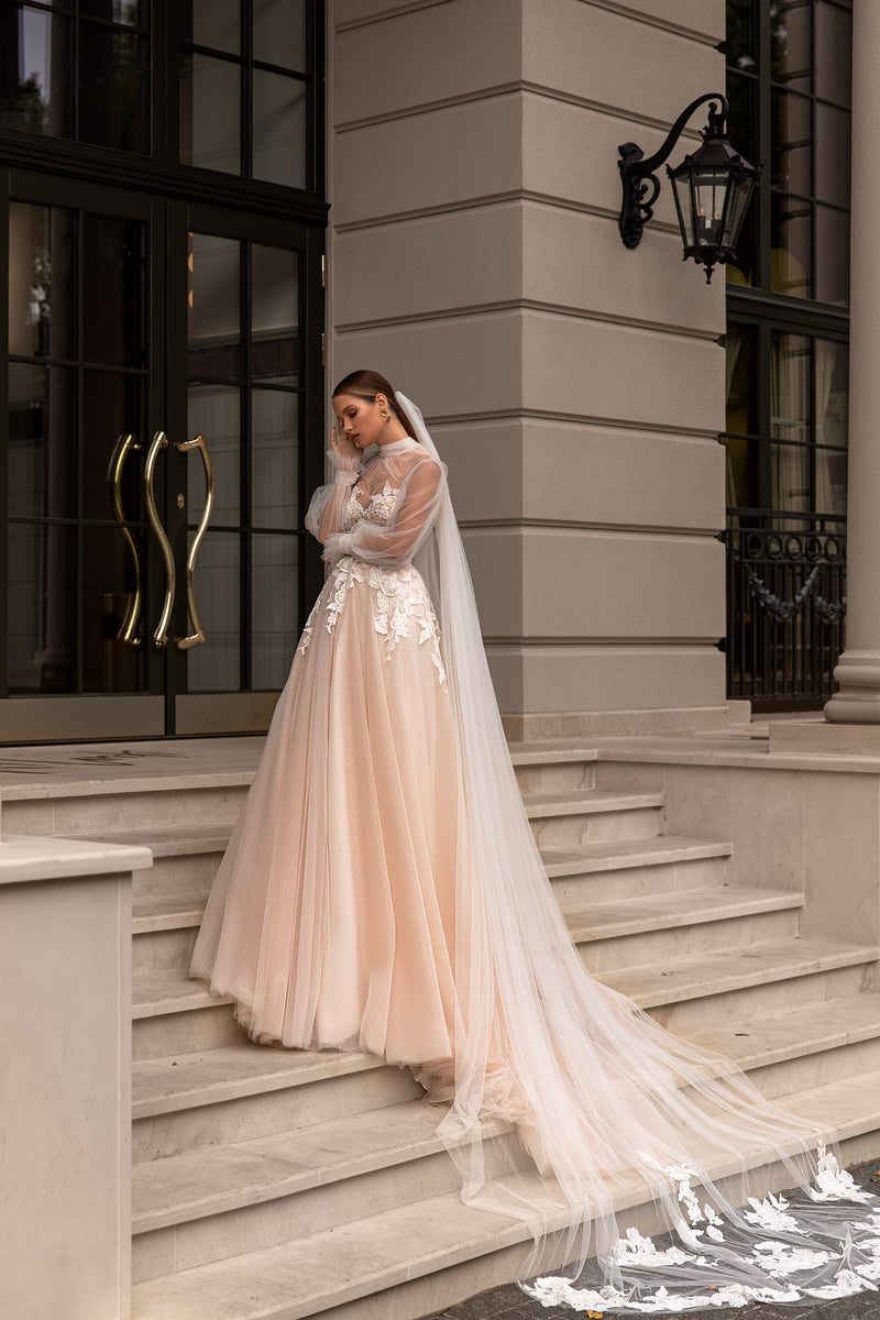 Cappuccino wedding dress with a beaded lace bodice, sheer long sleeves, full tulle skirt, and sweeping train