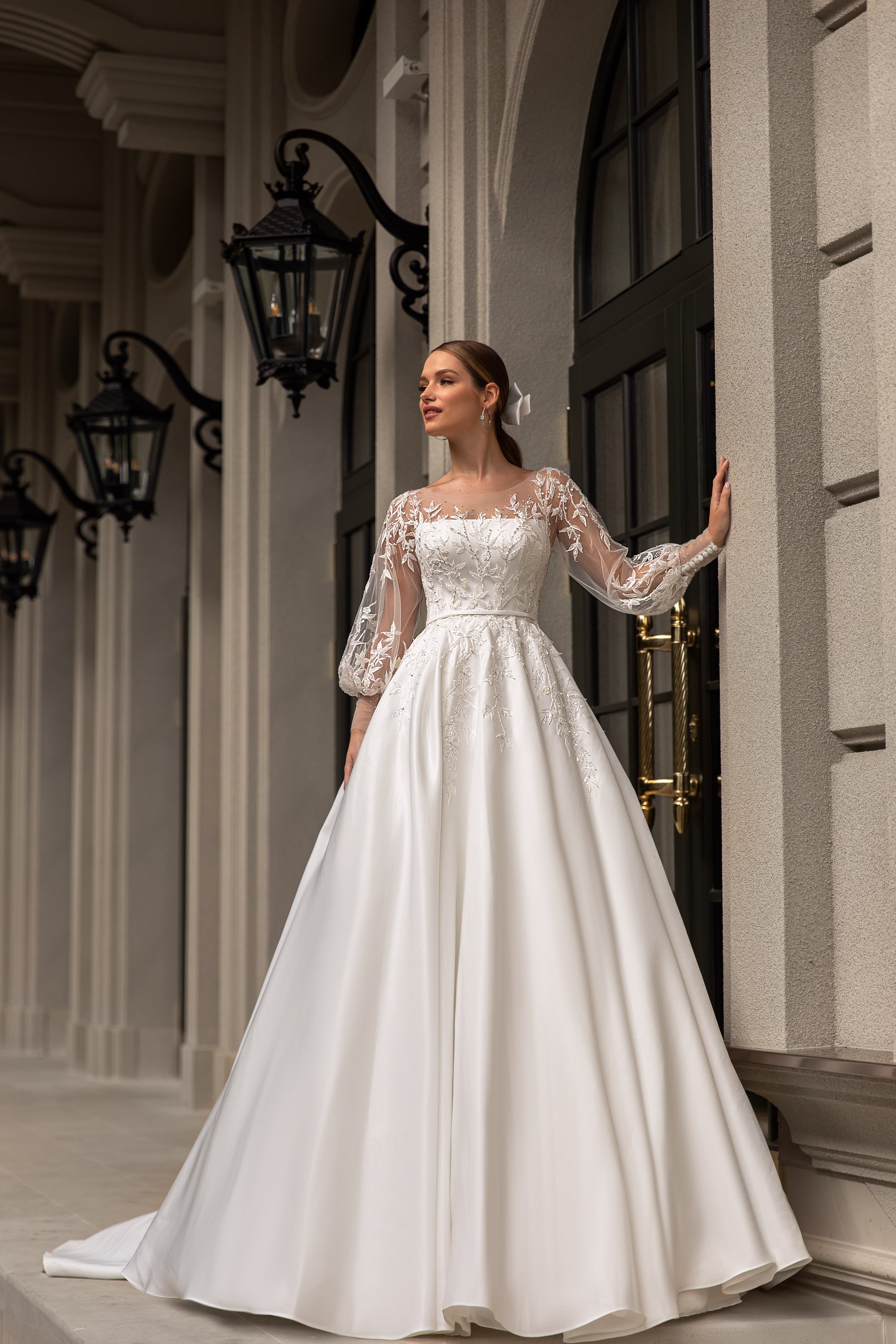 Ivory A-line wedding dress with a straight neckline, sheer lace sleeves, and a flowing satin skirt