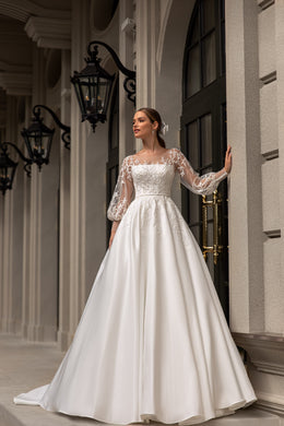 Ivory A-line wedding dress with a straight neckline, sheer lace sleeves, and a flowing satin skirt