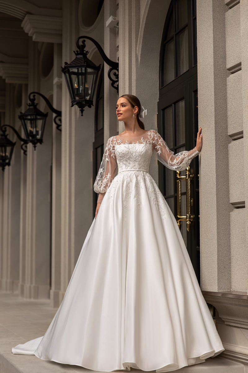 Ivory A-line wedding dress with a straight neckline, sheer lace sleeves, and a flowing satin skirt