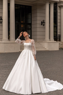 Ivory wedding dress with long lace sleeves, floral bodice appliqués, a full A-line skirt, and a train