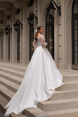 Back view of an ivory wedding dress with a sheer lace back, long sleeves, and an extended train