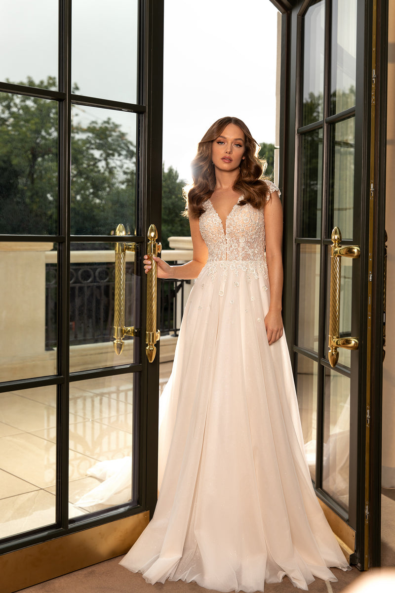Ivory wedding dress with a deep V-neck, beaded bodice, sleeveless design, and flowing full skirt