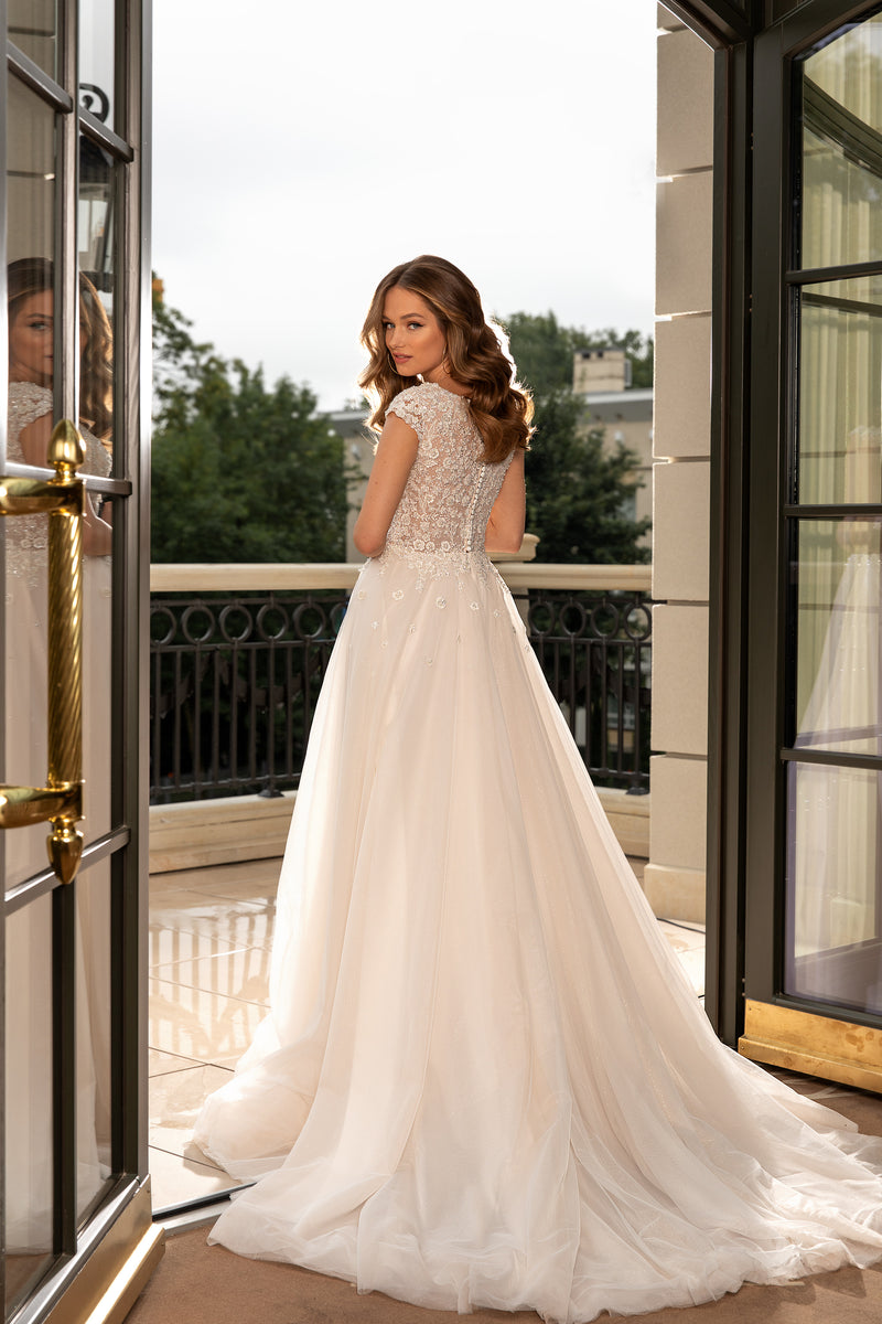 Ivory wedding dress showing a lace-covered back, embellished bodice, and sweeping floor-length train