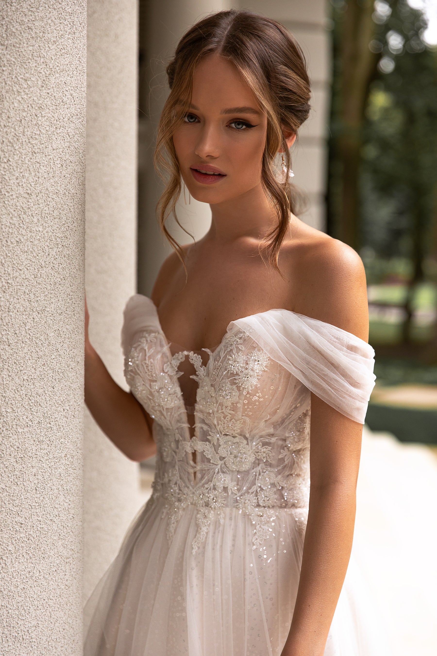 Close-up of an ivory wedding dress bodice with floral lace, beadwork, sweetheart neckline, and sheer sleeves
