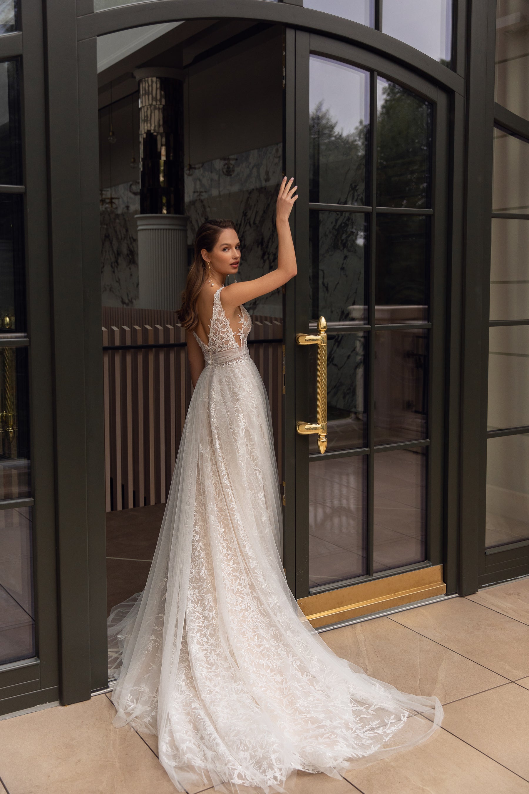 Open-back ivory wedding dress with thin straps, floral lace, an A-line skirt, and a long train