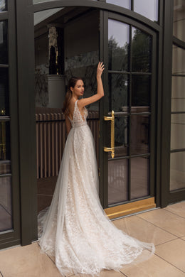 Open-back ivory wedding dress with thin straps, floral lace, an A-line skirt, and a long train