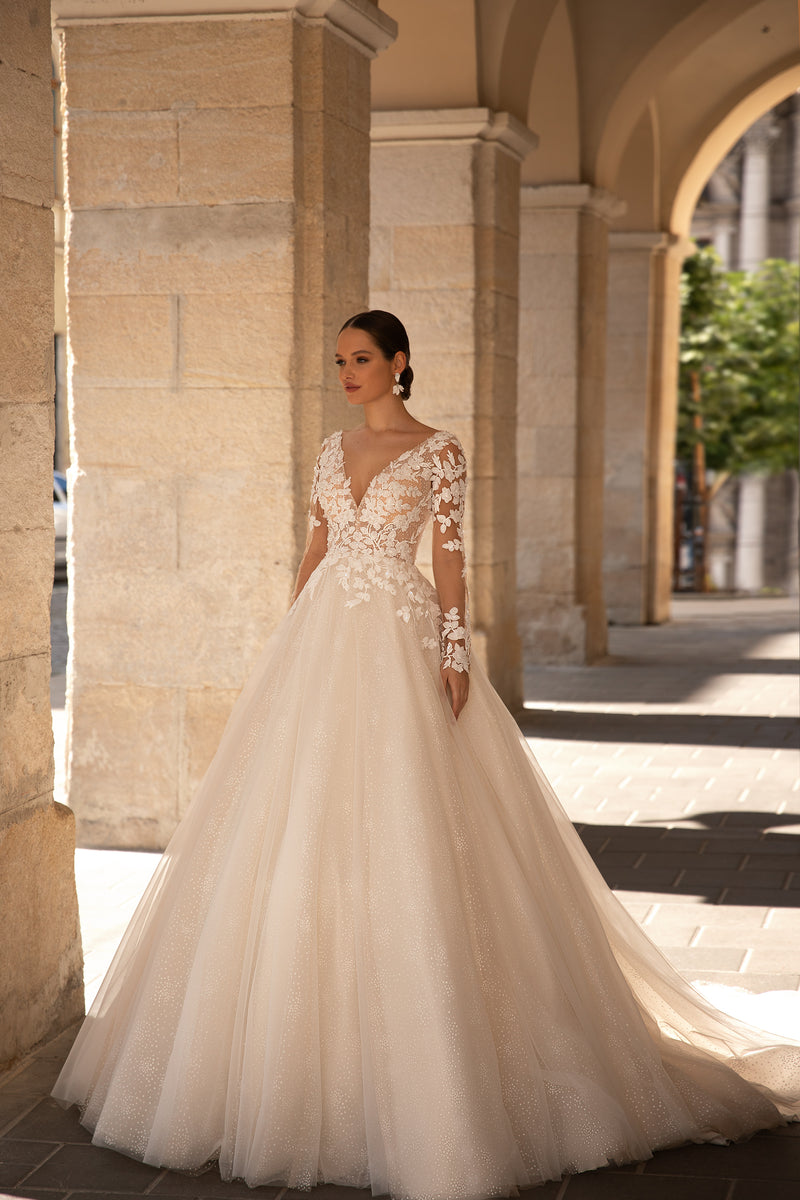 Ivory ball gown wedding dress with a deep V-neckline, sheer floral lace sleeves, and a full sparkling skirt