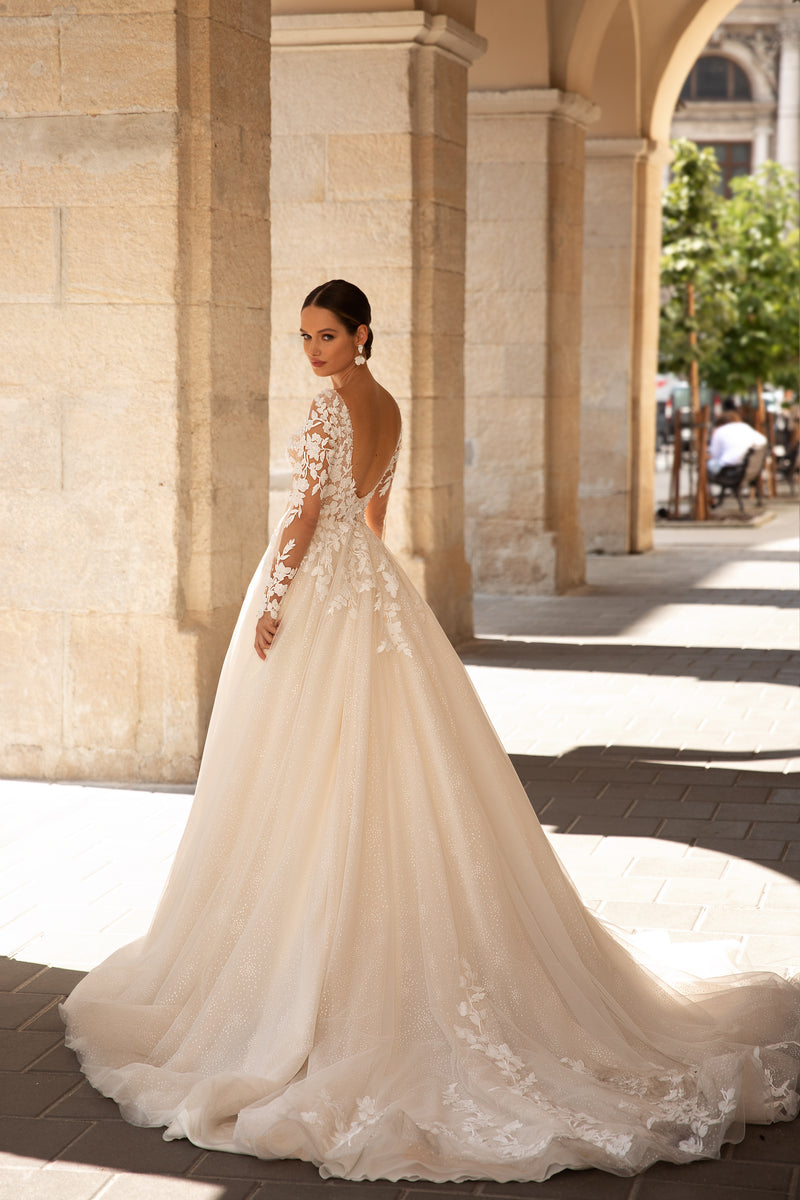 Open V-back wedding dress with floral lace sleeves, a full ivory skirt, and a long scalloped train