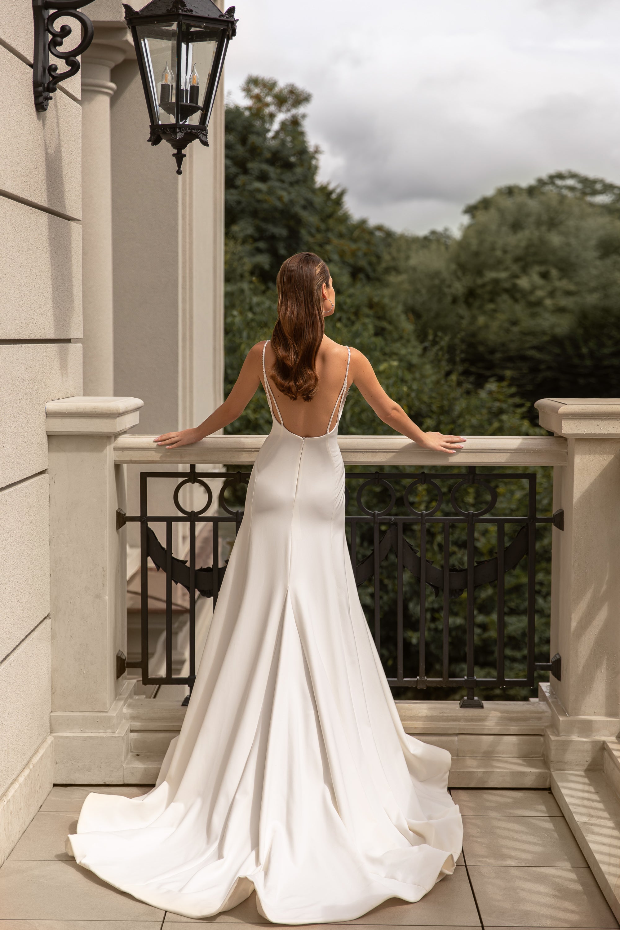 Open low-back ivory wedding dress with thin straps, a flowing skirt, and long train