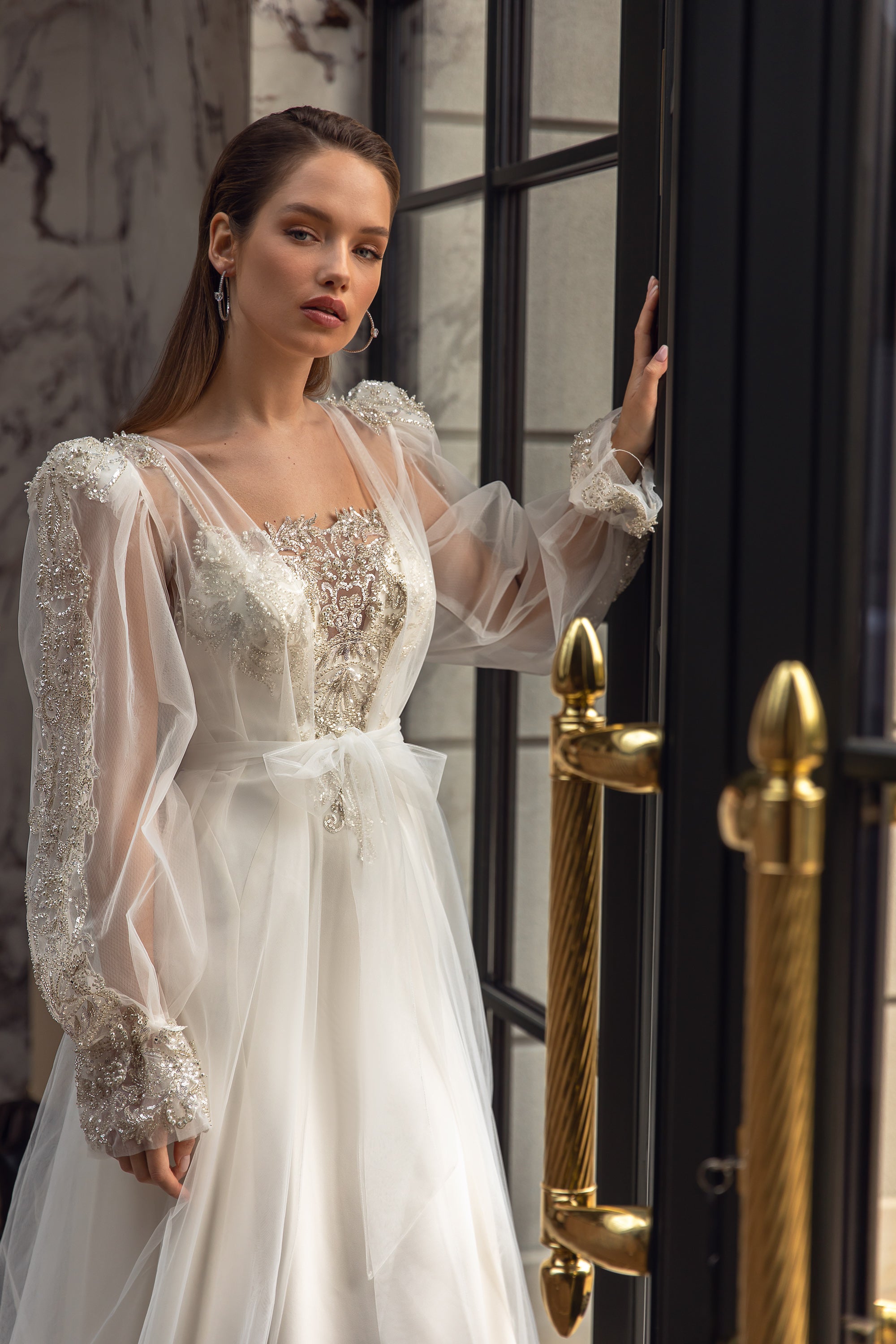 Close-up of sheer puff sleeves, jeweled cuffs, and ornate beadwork on a wedding dress