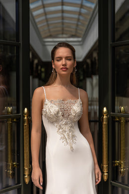 Ivory wedding dress with thin straps and dense floral beadwork across the fitted bodice